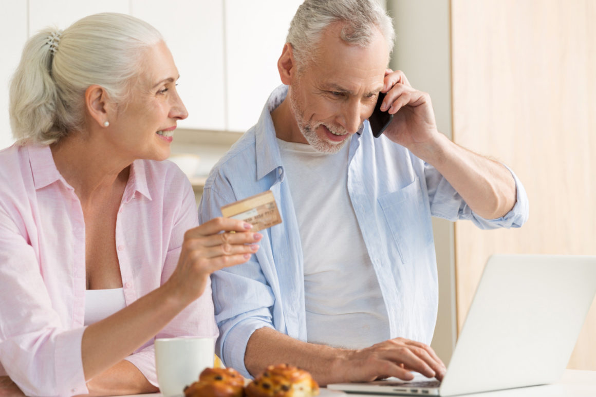 Un couple de retraités, sourient, en train de faire un crédit en ligne.