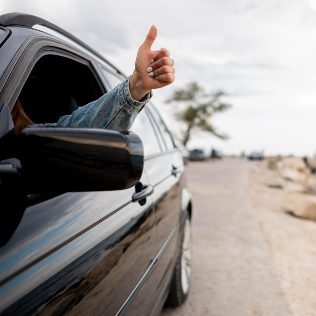 Main d'une jeune femme visible par la portière d'une voiture, connotant le rachat de crédit véhicule.